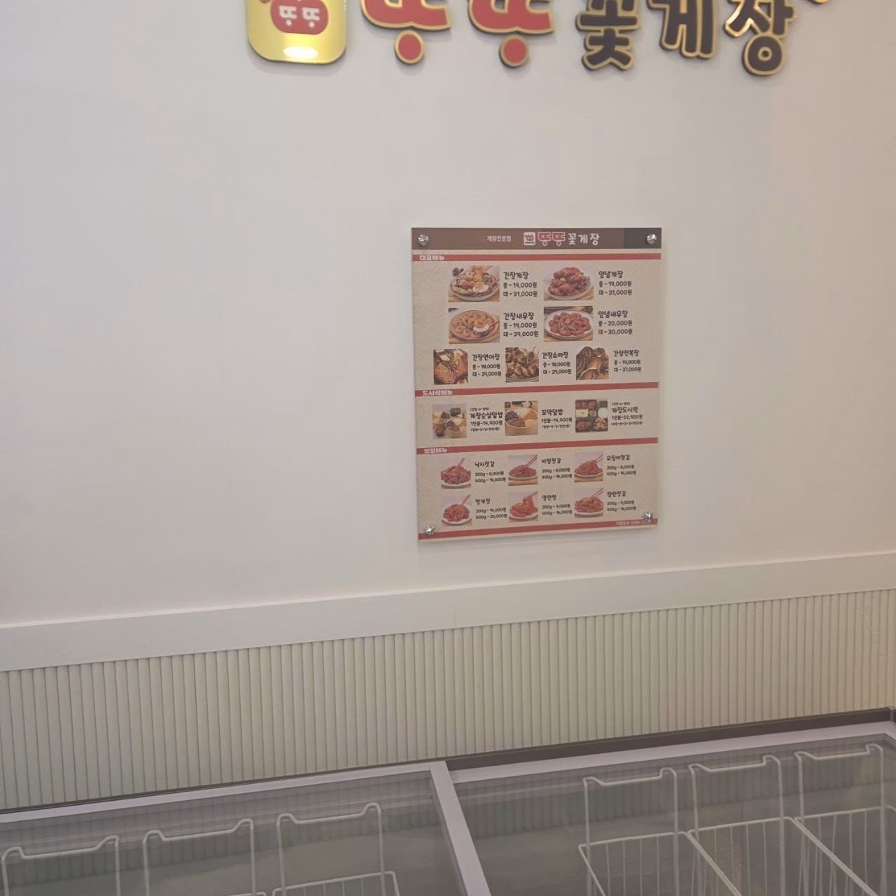 '또또꽃게장' 간판 아래 걸린 액자형 메뉴판